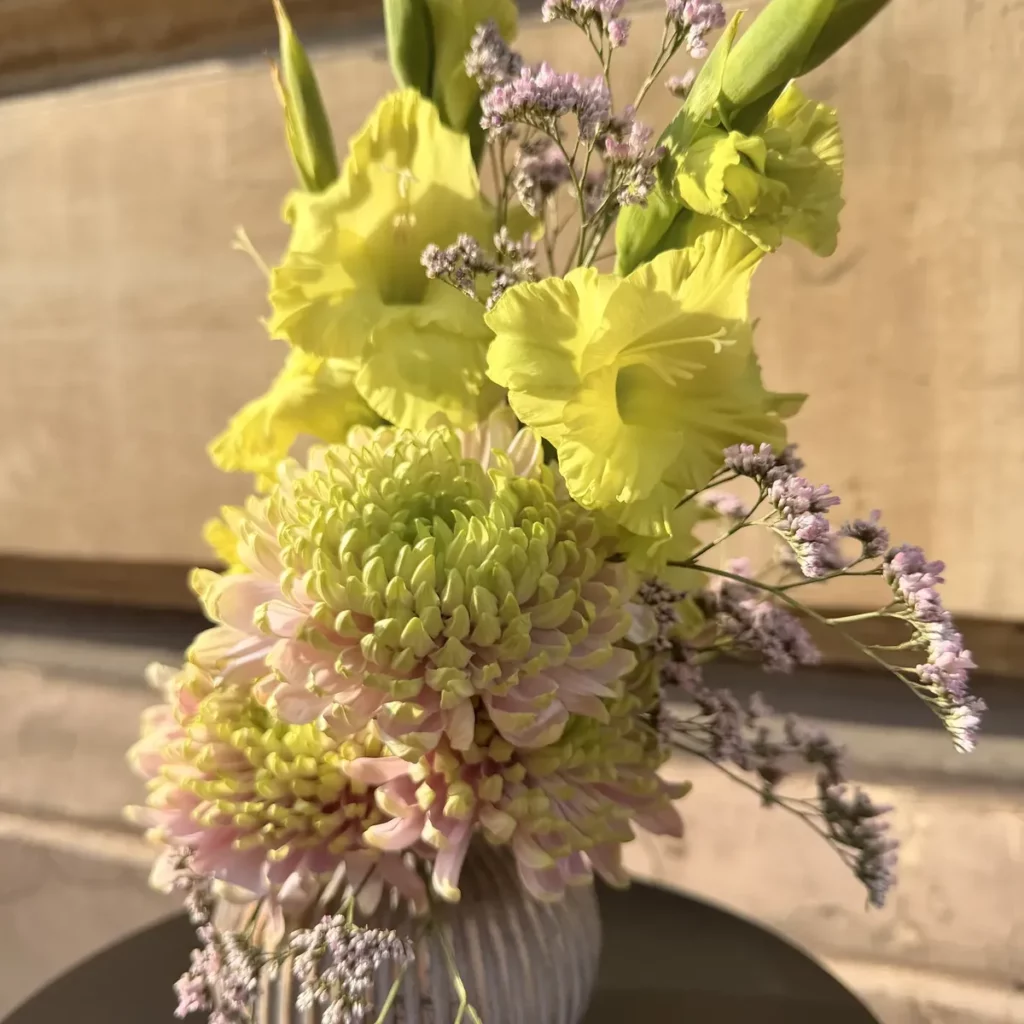 Kompozycja z żółtych mieczyków, chryzantem i limonium w prążkowanym wazonie